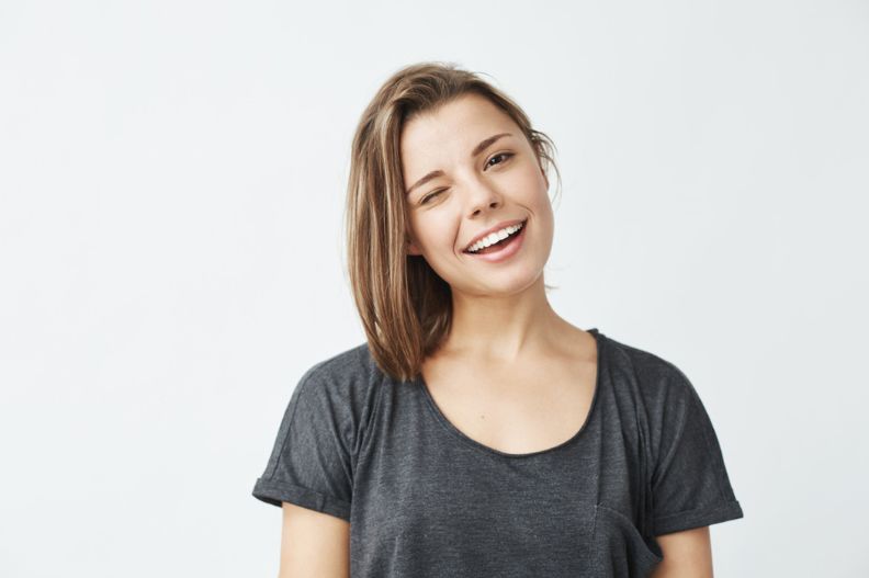 chica joven sonriendo y guiñando un ojo