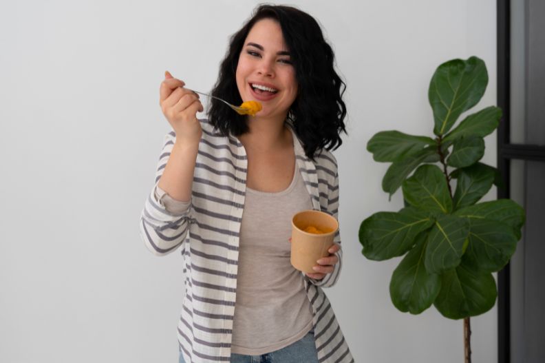 mujer joven comiendo mientras de pie mientras sonrie